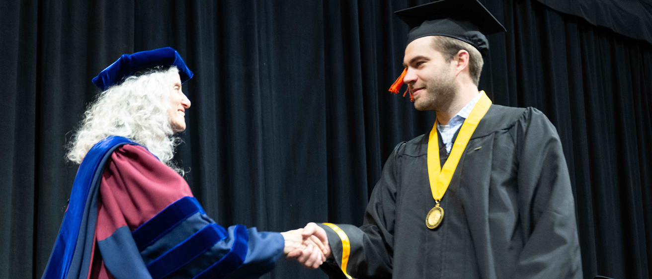 an engineering graduate shakes hand with the departmental executive officer at commencement