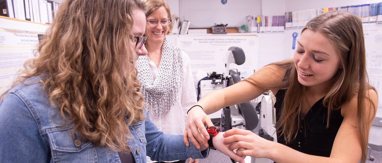 a woman places a fitness tracker on another woman's wrist