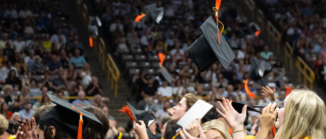 graduates throwing their caps in the air at a university of iowa college of engineering commencement ceremony