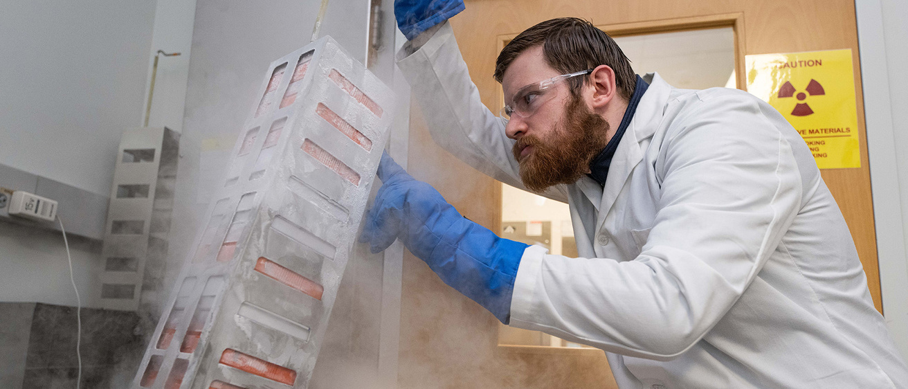 a researcher lifting equipment that appears to be emitting vapor or smoke