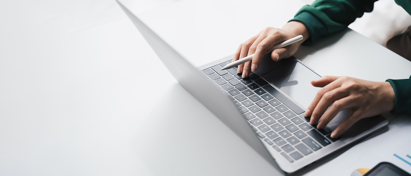 hands on the keyboard of a laptop computer that sits on a stark surface; it gives a sense of isolation, perhaps