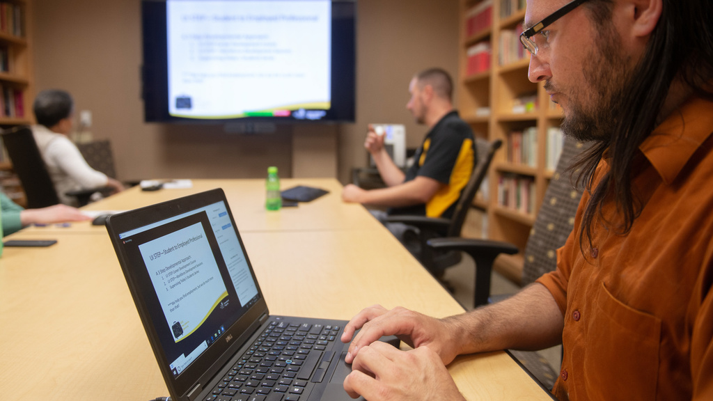 Man typing on computer conducting online seminar for international students.