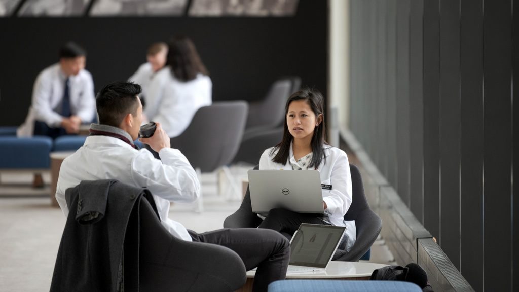 Pharmacy students talking to each other in pharmacy building space.