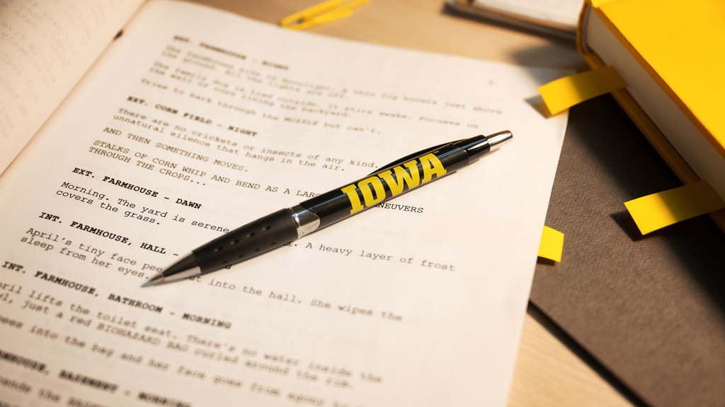 a pen with the Iowa logo rests upon a screenplay