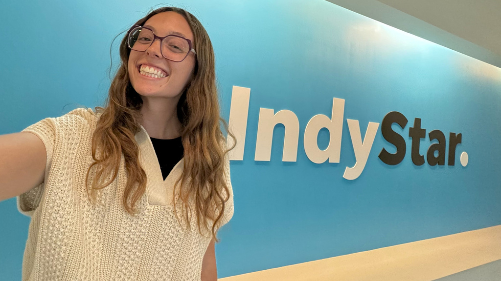 University of Iowa grad Grace Smith taking a selfie in front of the Indy Star logo on a wall