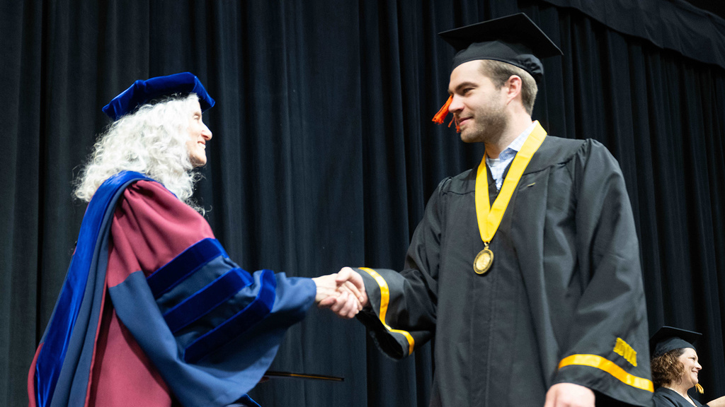 an engineering graduate shakes hand with the departmental executive officer at commencement