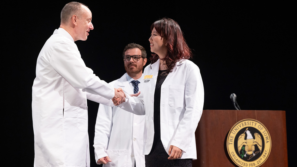 faculty congratulating a new med student at a white coat ceremony