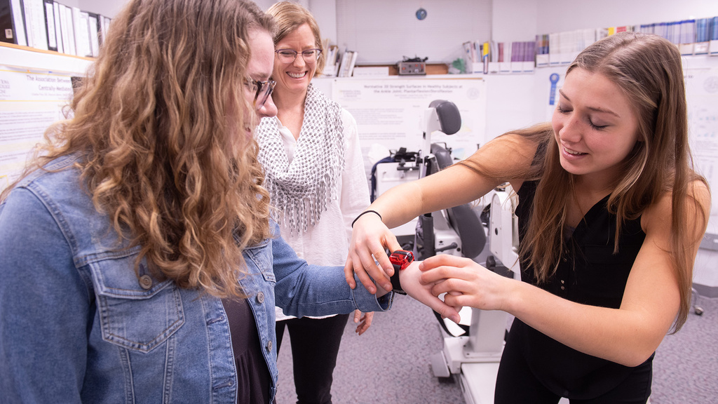 a woman places a fitness tracker on another woman's wrist