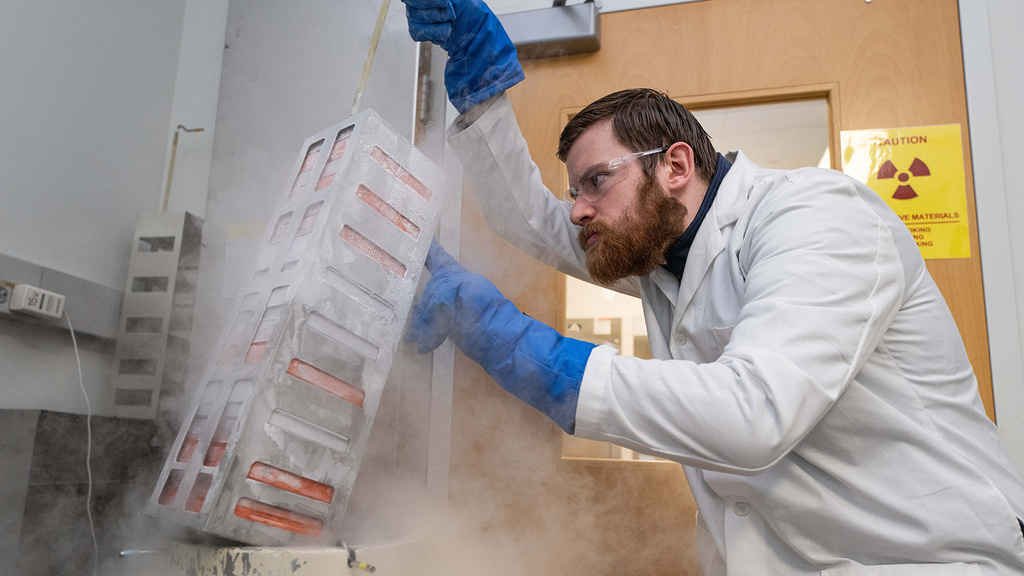 a researcher lifting equipment that appears to be emitting vapor or smoke