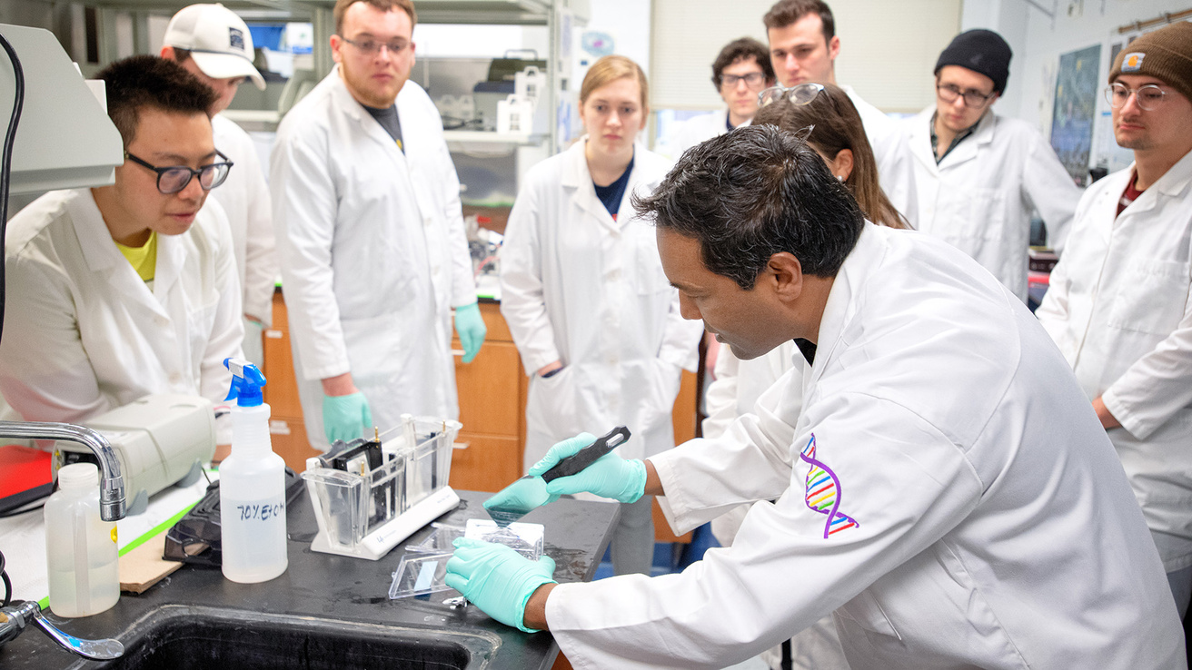 students and a professor in white coats in a biomedical engineering class