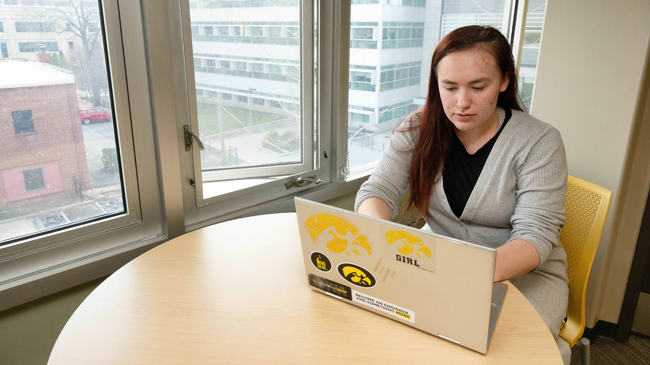 an engineering student in a study lounge working on a laptop