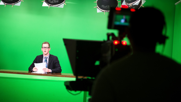 A student reads the news in front of a camera.