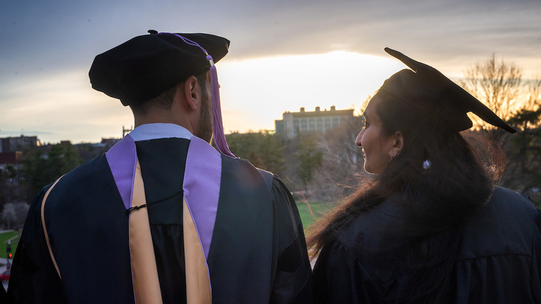 two grads standing outdoors on the university of iowa campus
