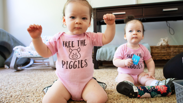 Two twin girls look at a camera and playing with toys