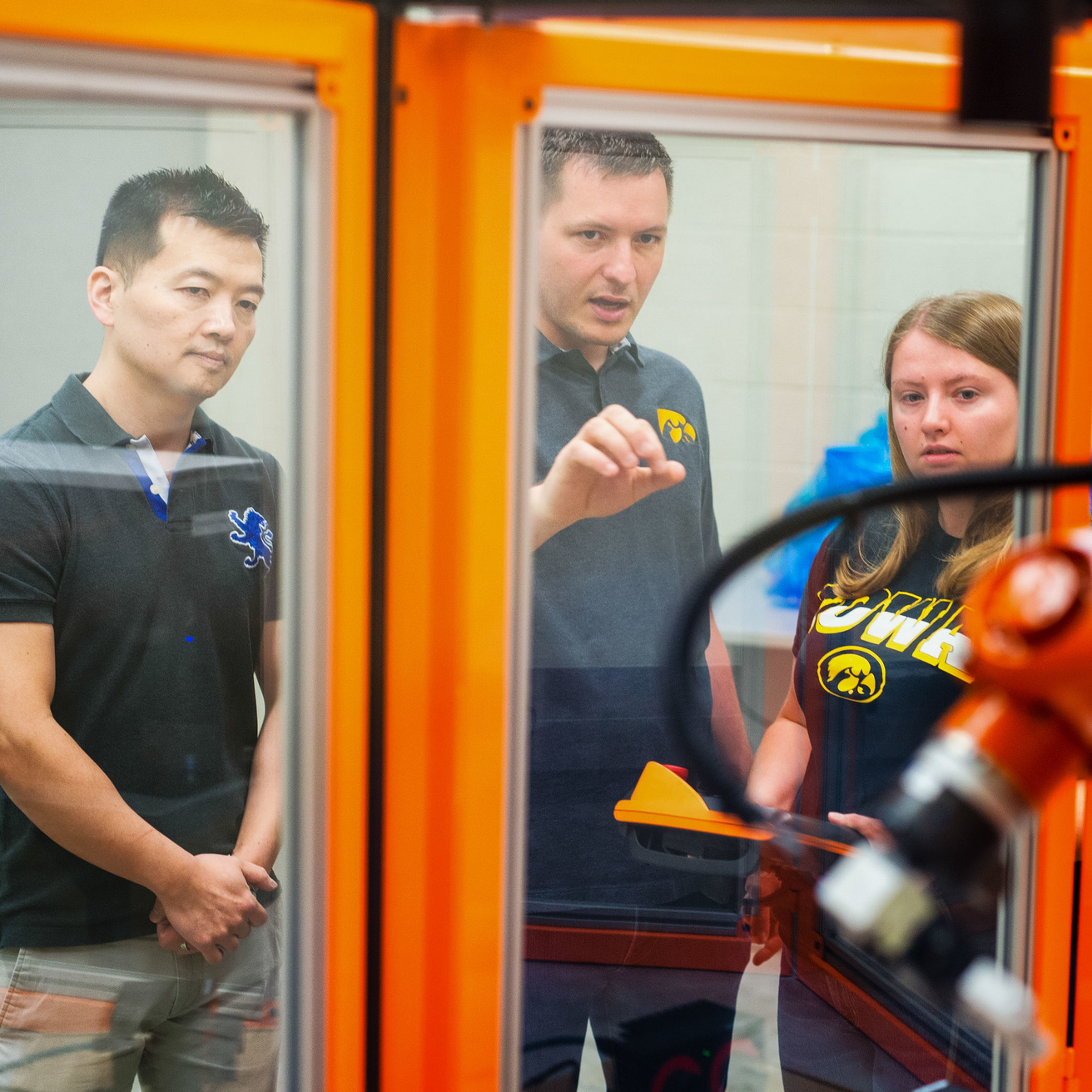 Professor works with two students in a robotics lab.