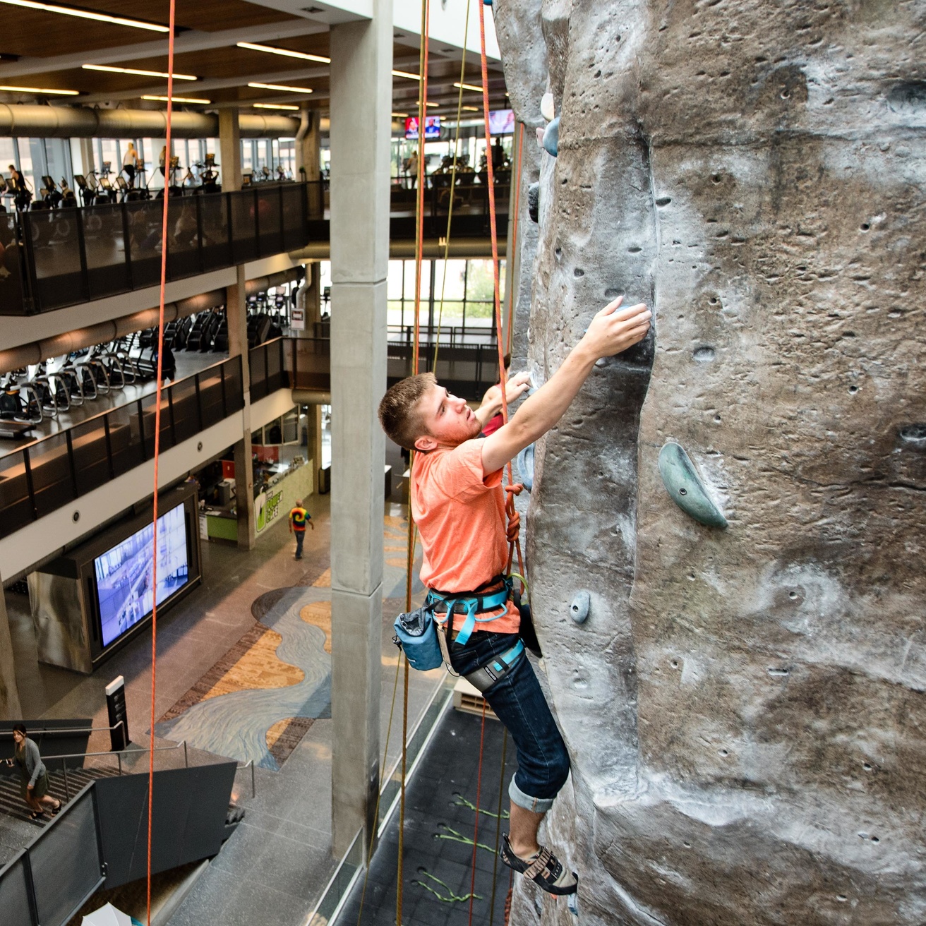 Student climbs a rock wall at the campus recreation building. 